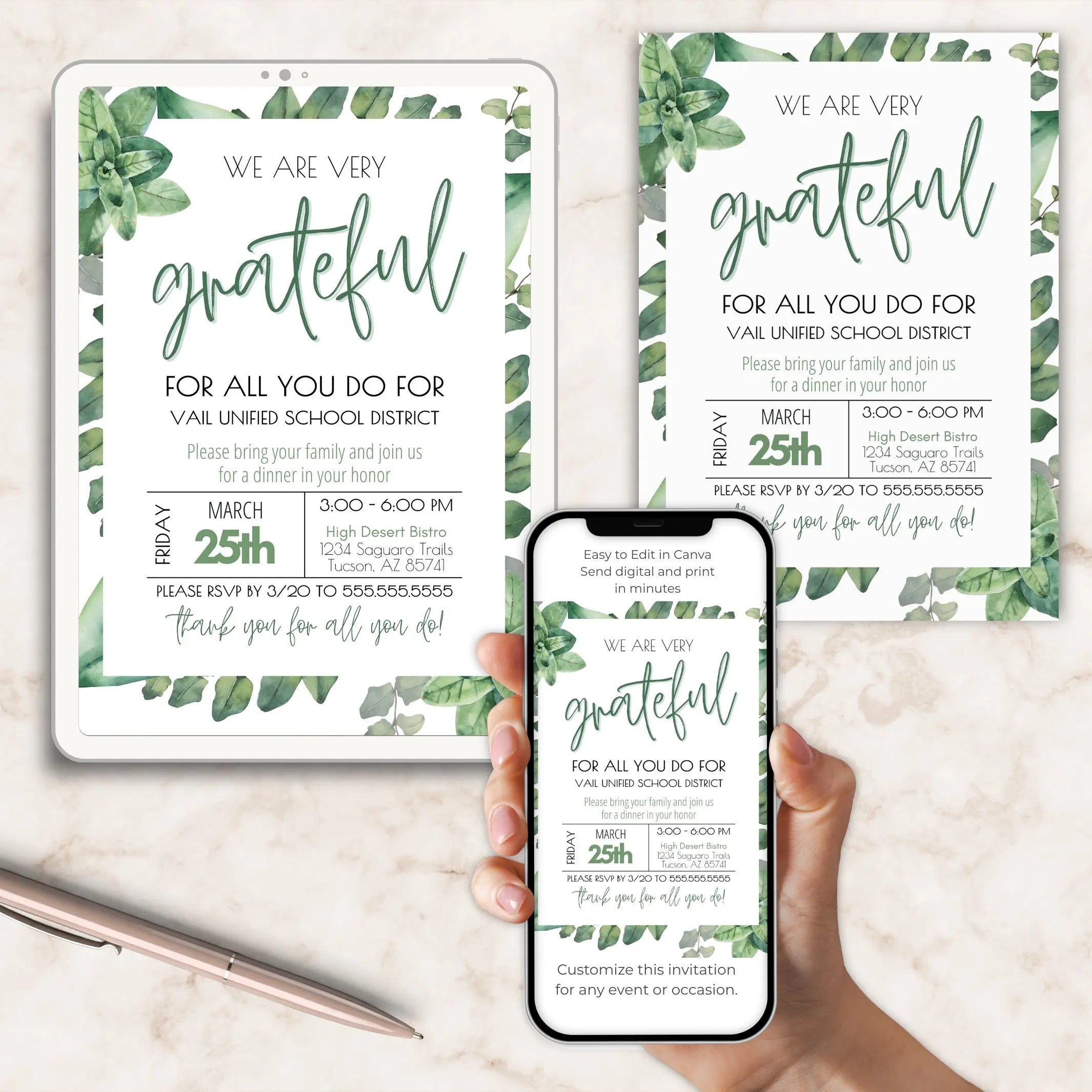 Invitation cards with greenery design and a phone and tablet displaying the invitation on a marble surface.