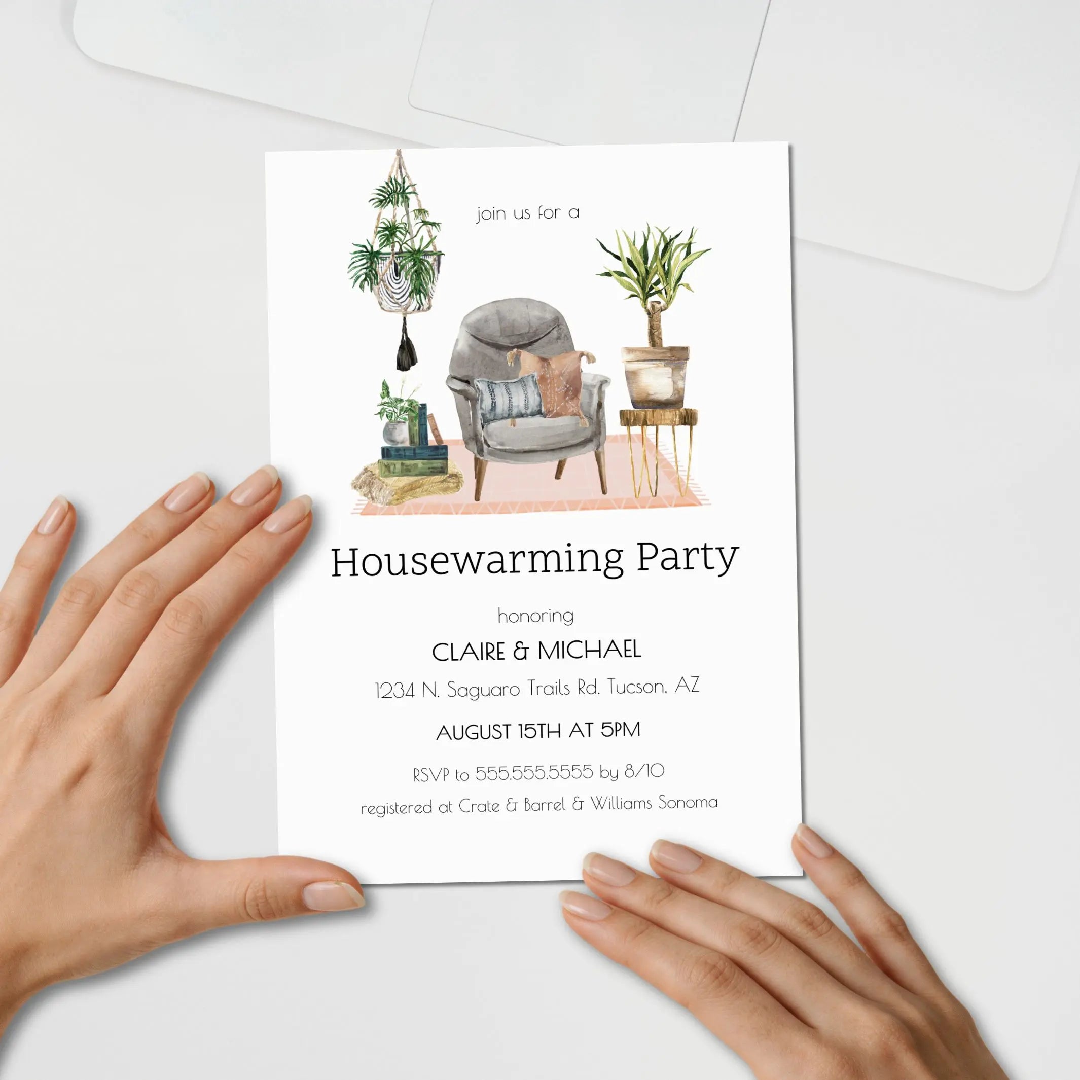 A housewarming party invitation card held by two hands against a light gray background. The card features a watercolor illustration of a cozy living room scene with a gray armchair, potted plants, and books, above black text reading 'Housewarming Party' and event details.