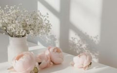 Pink flowers in a vase on a white surface with a light background