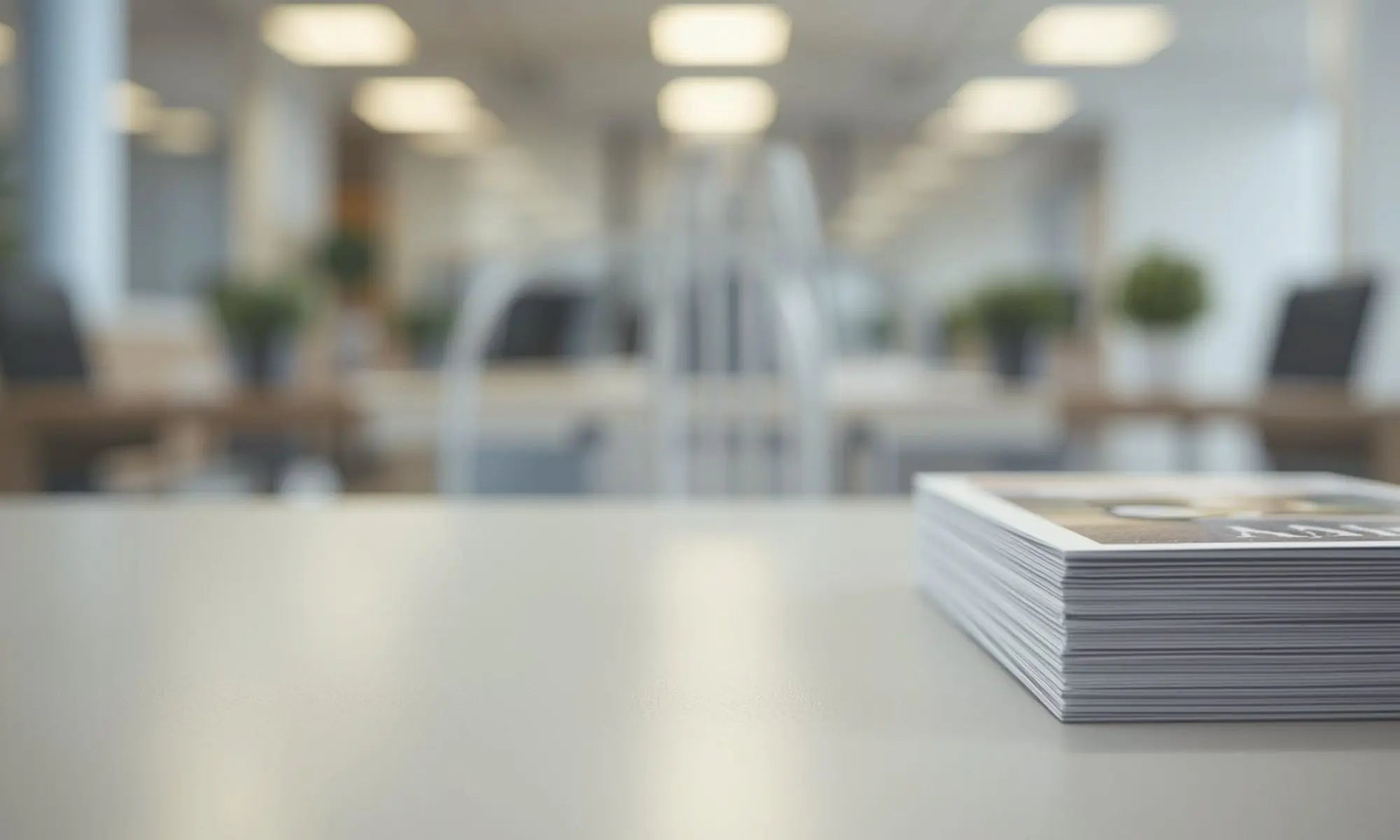 stack of flyers on a neutral desk space in room with greenery and plants