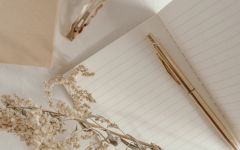 Neutral notebook with a gold pen and dried florals on a soft backdrop, representing creativity and peaceful design planning.