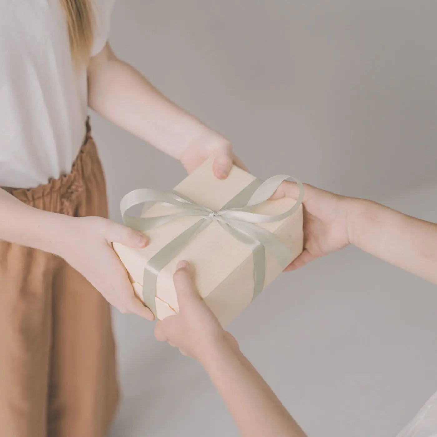 Two people exchanging a gift box with a green ribbon against a neutral background representing editable appreciation and recognition event and invitation templates.