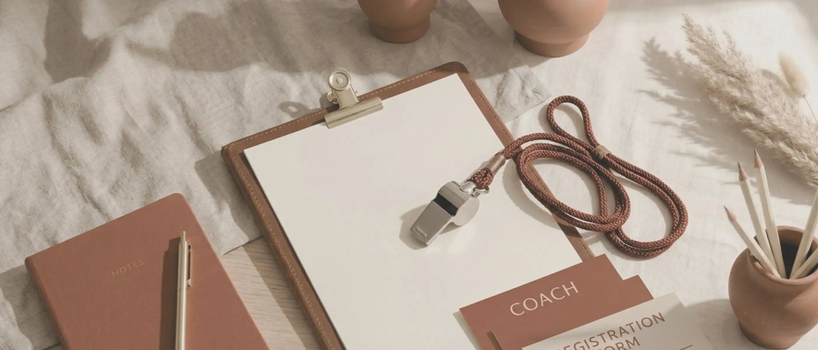 Clipboard with a whistle, lanyard, and notebook on a textured surface representing a collection of editable templates and resources for coaches and team events created by Simple Desert Designs.