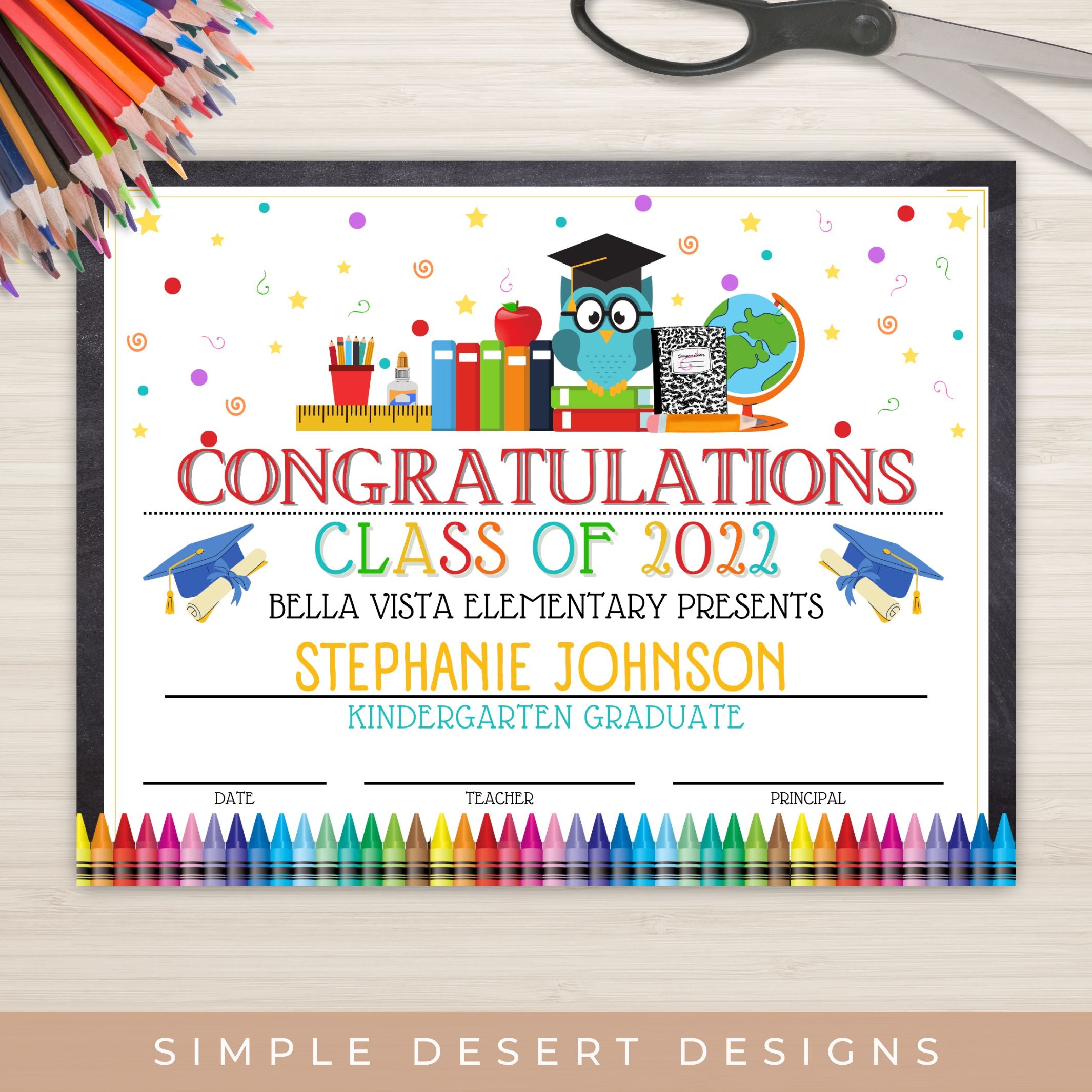 Graduation certificate for a kindergarten graduate with colorful border and stationery items on a wooden surface.