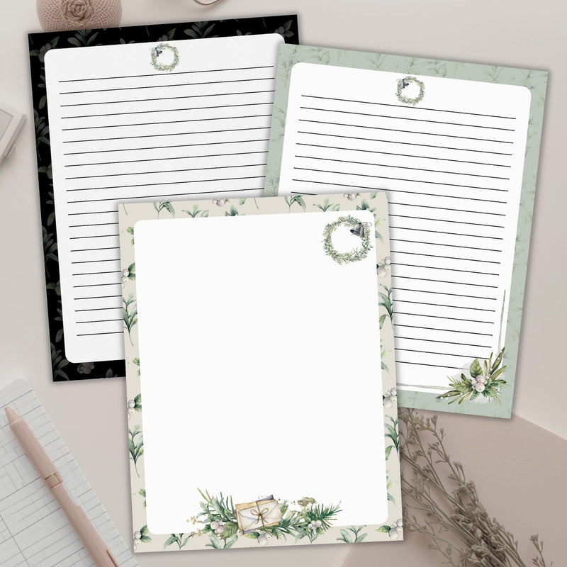 Three decorative sheets of lined and unlined botanical stationery paper with floral designs on a light surface.