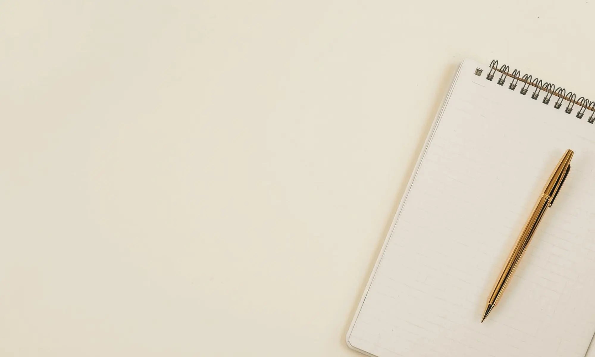 Notebook with a pen on a beige background representing a collection of free resources for teachers, parents, event planners, party hosts, coaches, professionals, and STR hosts by Simple Desert Designs.