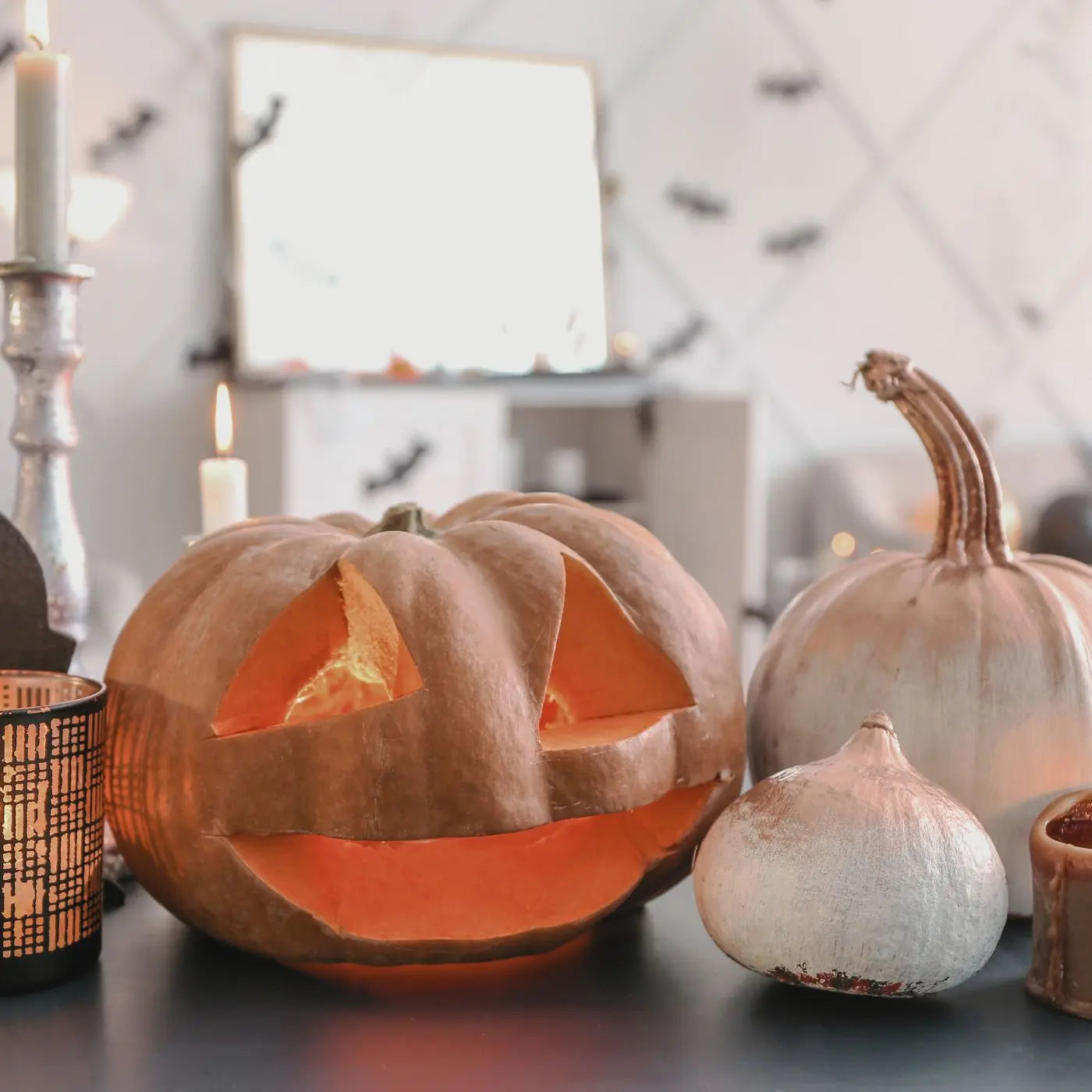 Carved pumpkin with candle inside on a table with decorative pumpkins and candles representing editable invitations, flyers, tags, and event bundle templates by Simple Desert Designs.