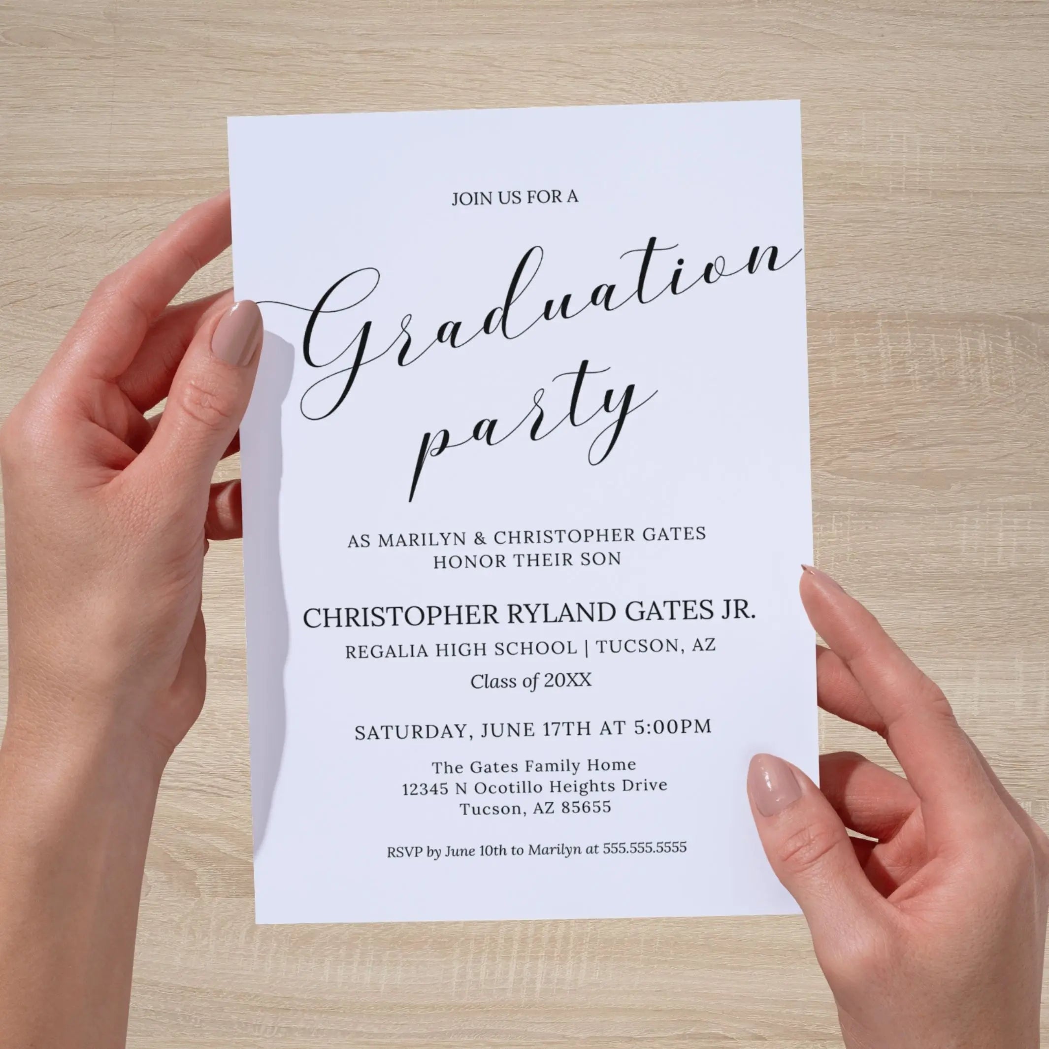 Graduation party invitation held by hands on a wooden surface