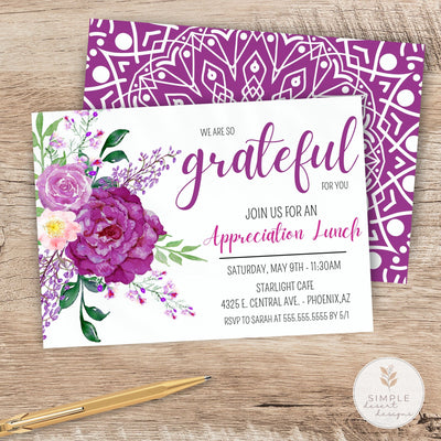 Invitation card with purple floral design and geometric pattern on a wooden surface.
