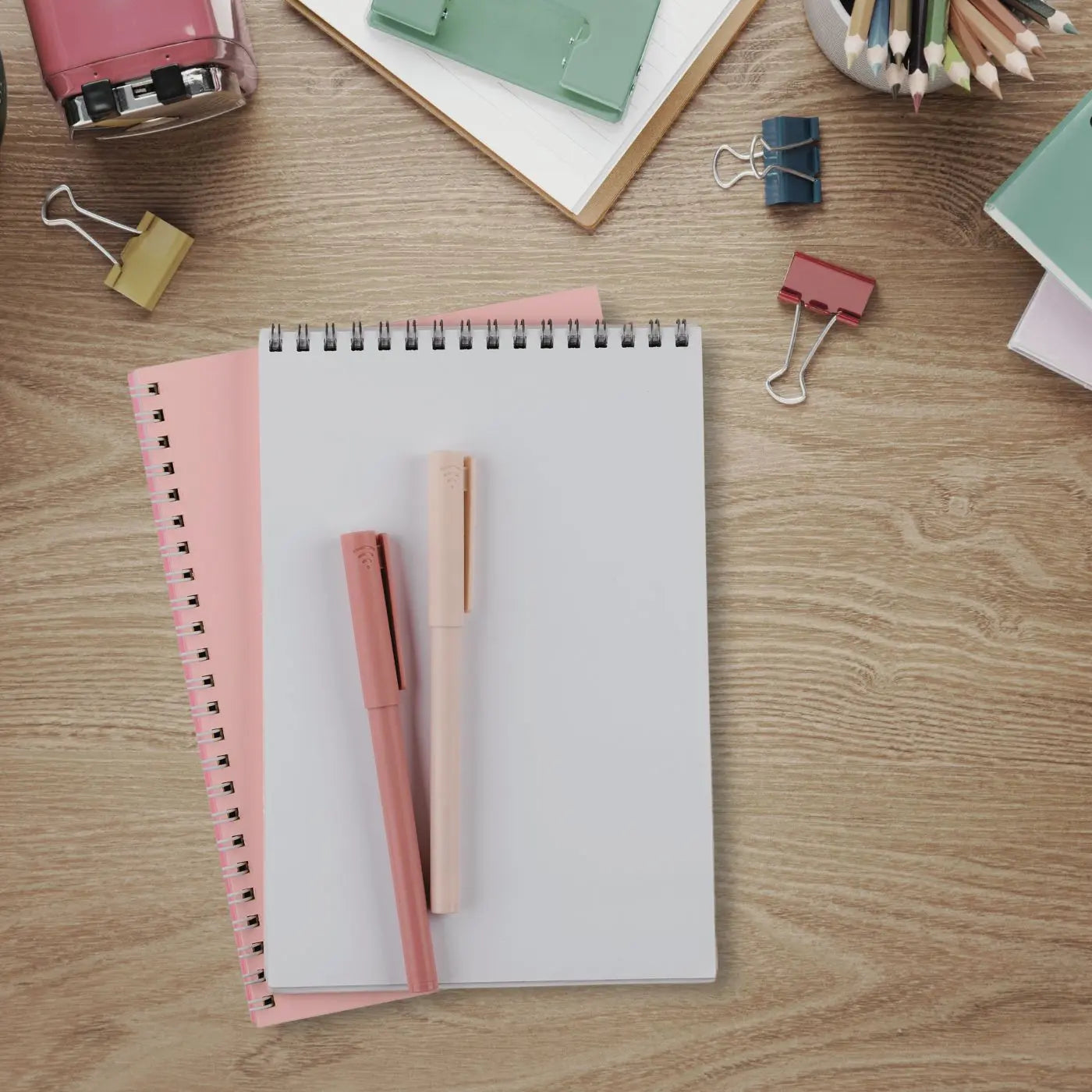 Notebook with pink pen and clips on a wooden surface representing editable event templates for school, youth, and family events.